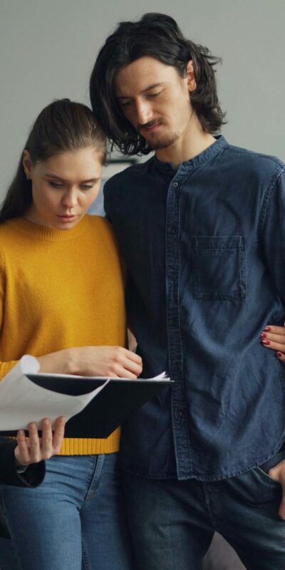 A couple reviewing documents with a real estate agent indoors.