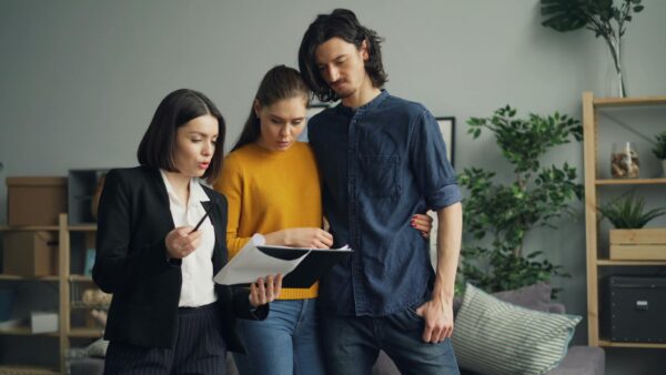 A couple reviewing documents with a real estate agent indoors.