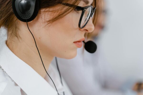 A young woman with glasses and headset intensely focused on her work in an office environment.