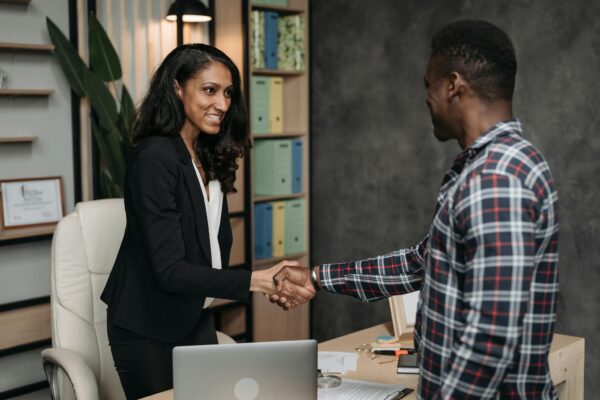 Two professionals shake hands in a modern office, symbolizing a successful agreement.